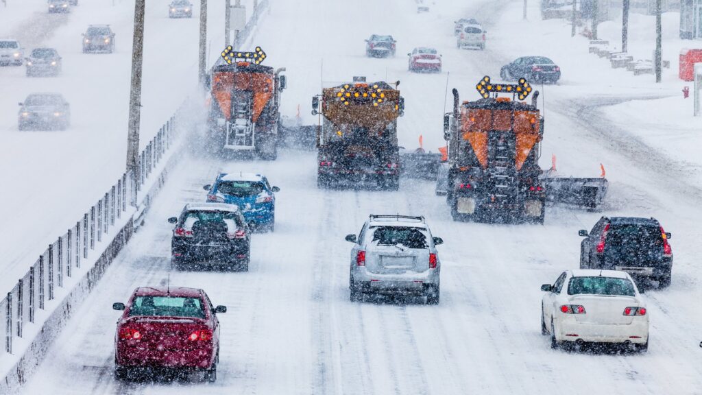 cars driving behind snow plow truck