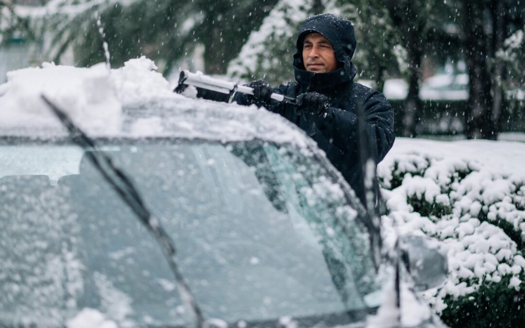 Man cleaning car in snow